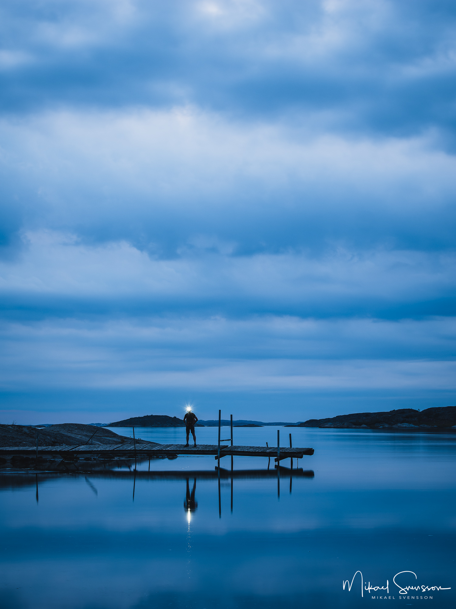 Man med pannlampa står på brygga vid Fåglevik, Hisingen.