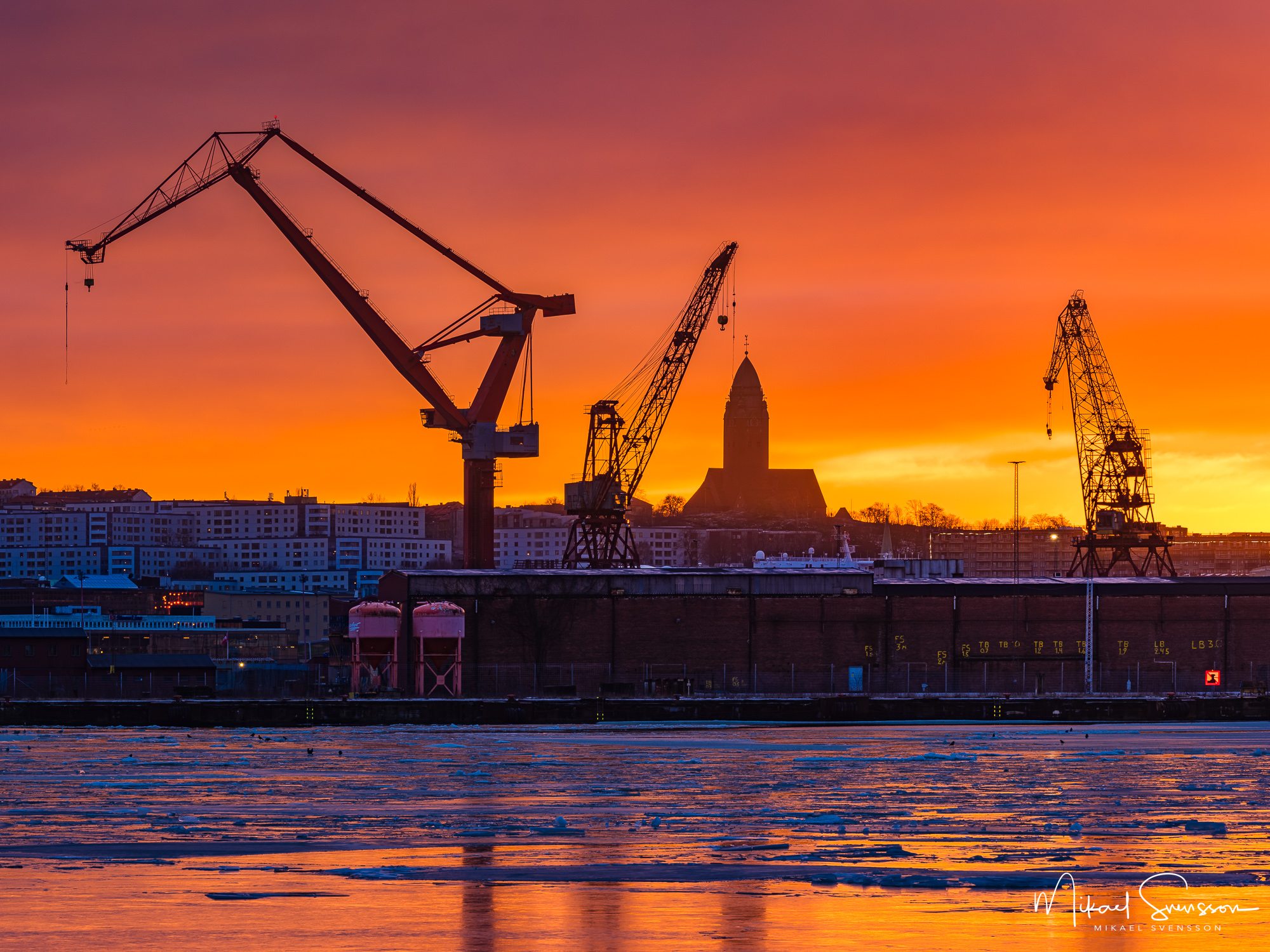 Vacker solnedgång i Lundbyhamnen med varvskranar och Masthuggskyrkan.