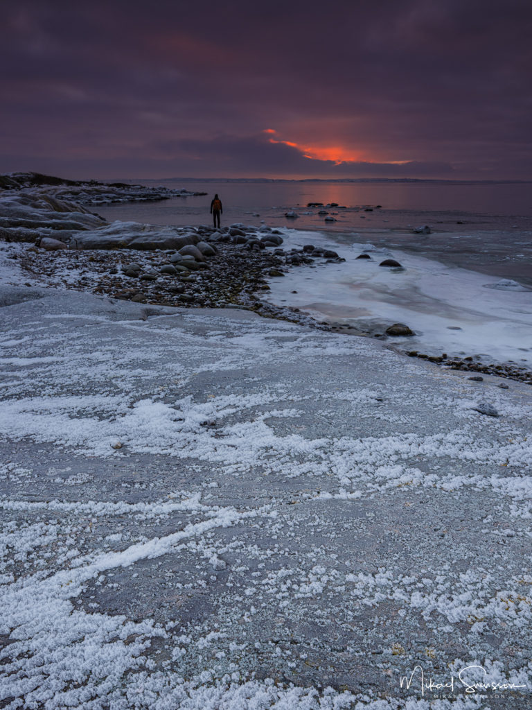 Man står på vinter klippa vid soluppgången. Hönö, Öckerö kommun
