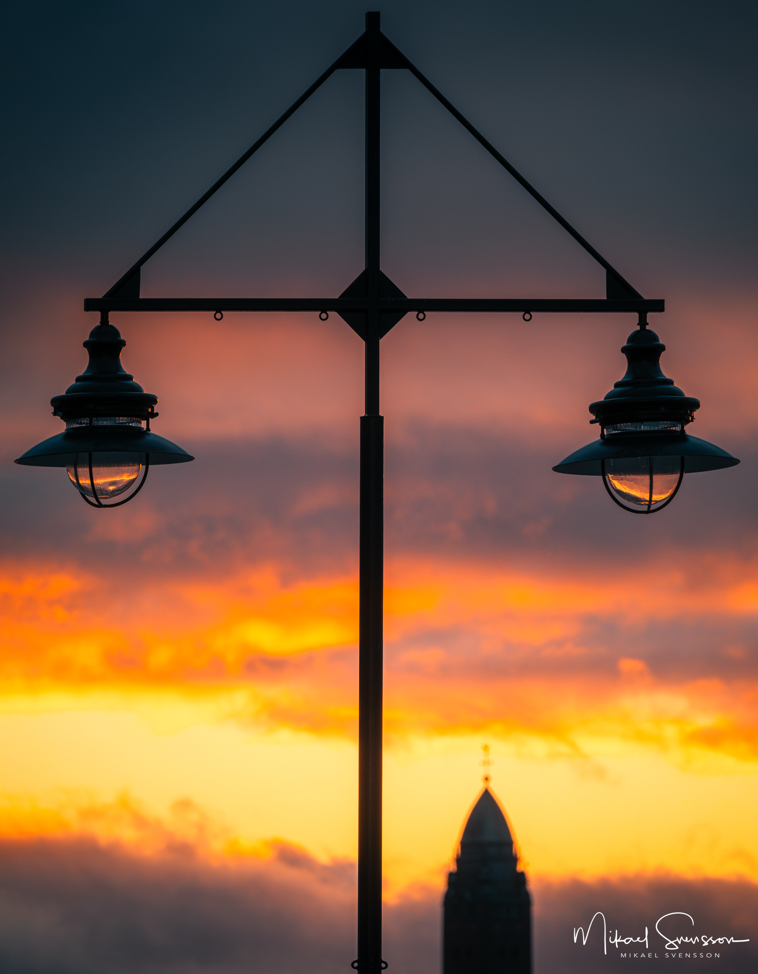 Gatubelysning vid vacker solnedgång längs kajkant, Göteborg.