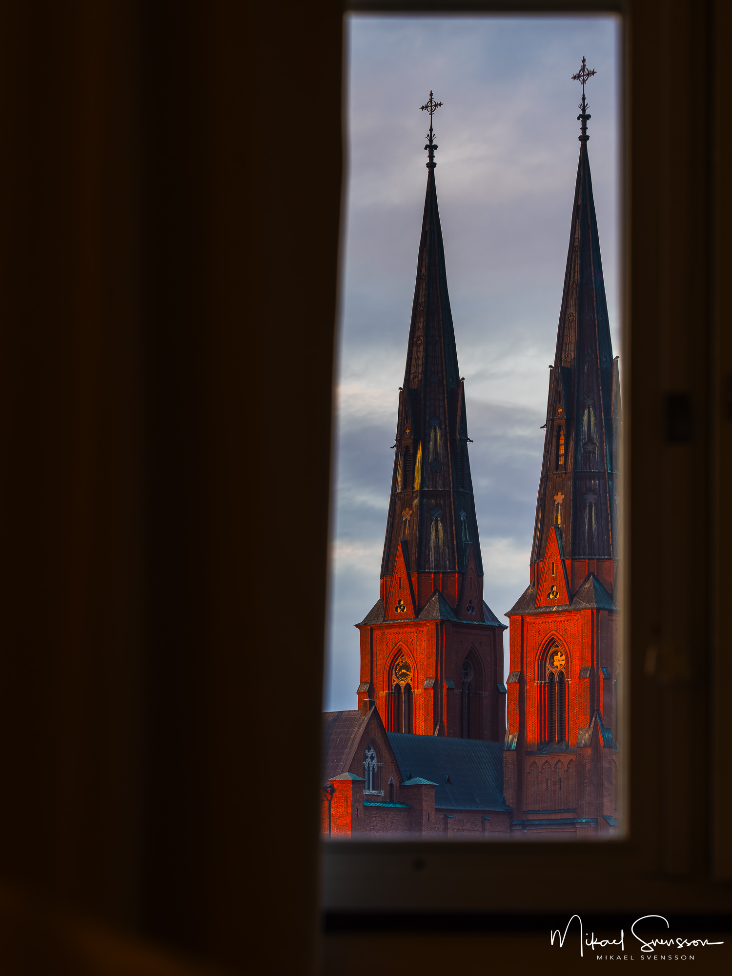 Soluppgång genom fönster mot Uppsala domkyrka