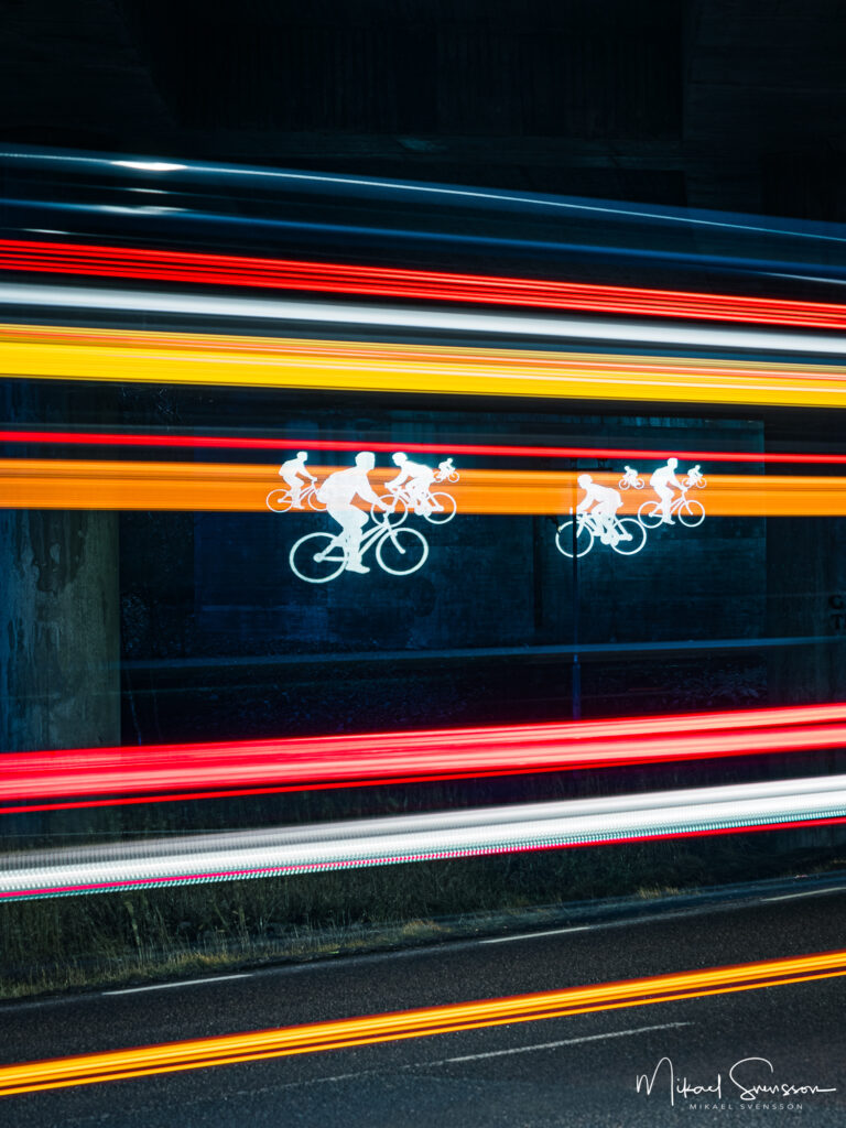 Trafik passerar under viadukt med cykelmotiv.